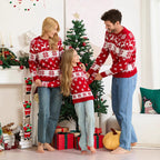 Family wearing matching red Christmas sweaters in a decorated living room.