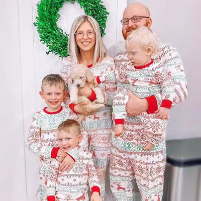 Family of four wearing matching pajamas with a Christmas tree in the background