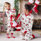 Woman and child in matching Christmas pajamas with stockings in the background.