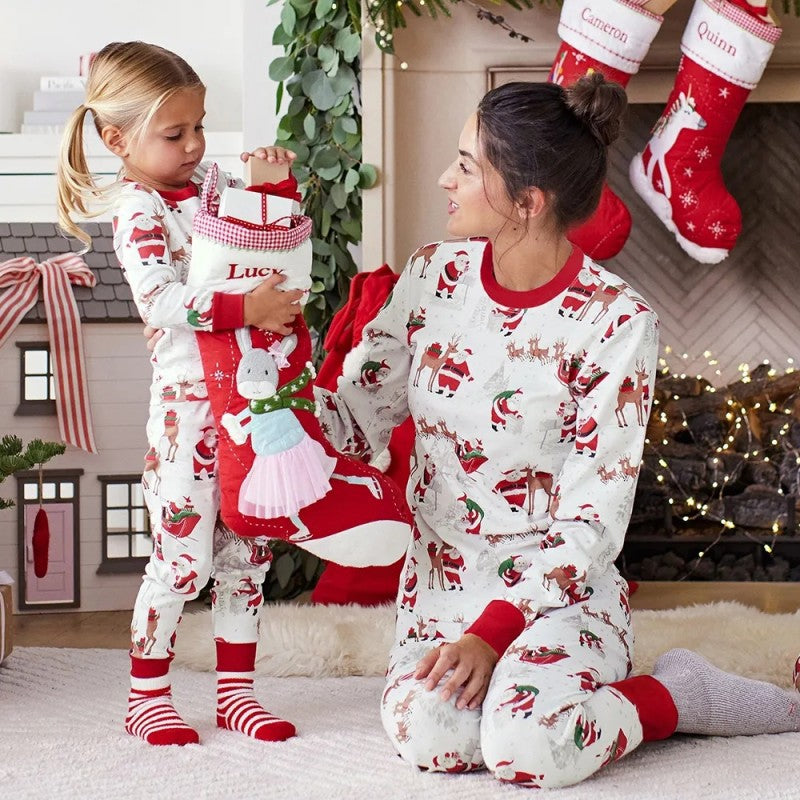 Woman and child in matching Christmas pajamas with stockings in the background.