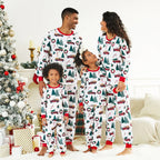 Family of four wearing matching Christmas-themed pajamas in a festive living room.