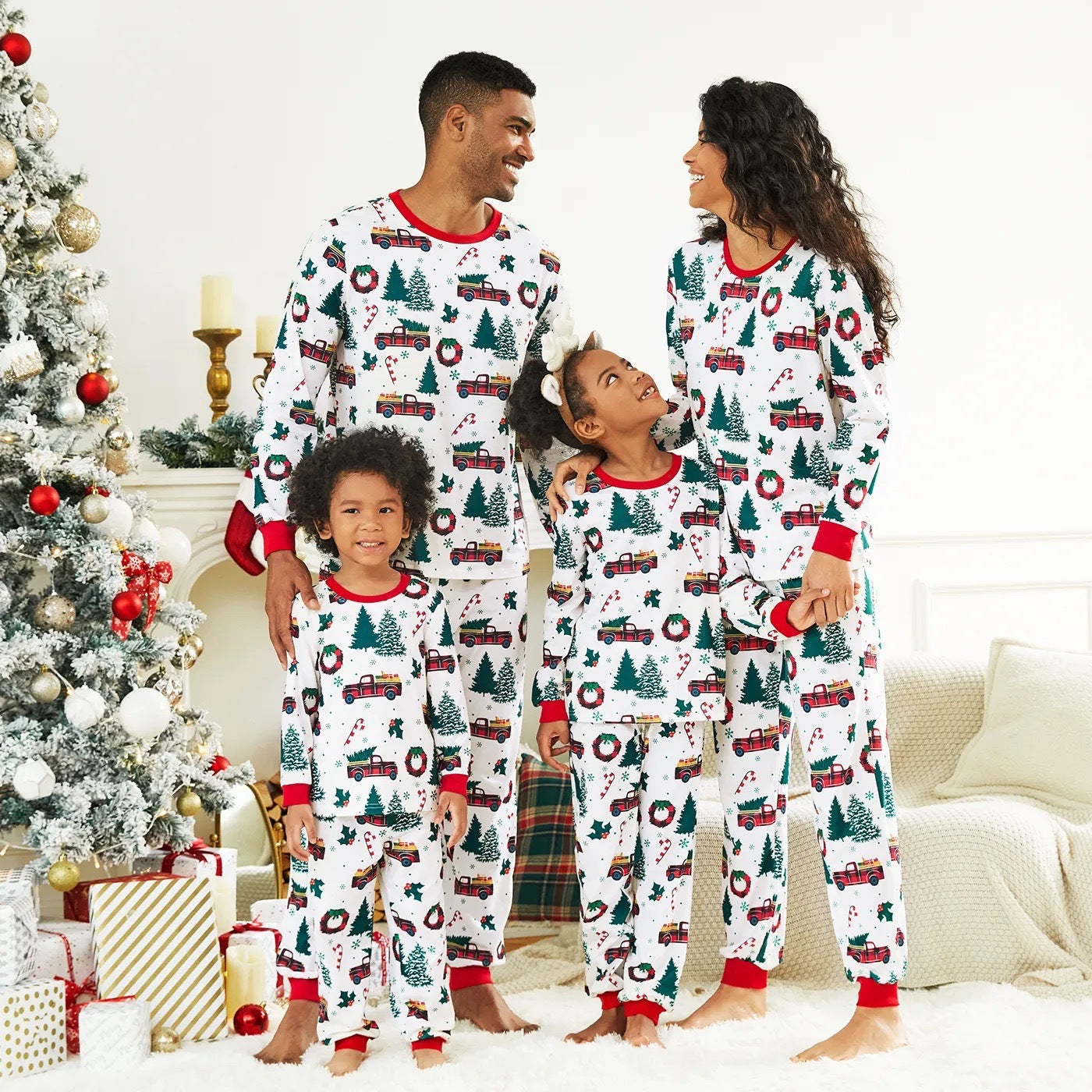 Family of four wearing matching Christmas-themed pajamas in a festive living room.