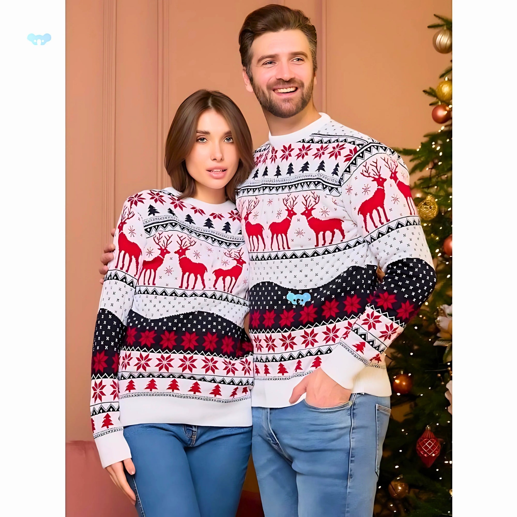 Two people wearing Christmas-themed sweaters in front of a decorated tree.