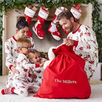 Family in matching pajamas with a red sack labeled 'The Millers' in front of Christmas stockings.
