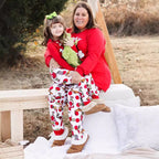 Woman and child in matching pajamas sitting on a wooden bench outdoors.