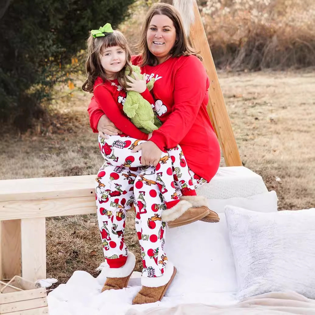 Woman and child in matching pajamas sitting on a wooden bench outdoors.