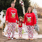 Family wearing matching 'Merry Grinchmas' outfits outdoors with Christmas decorations.